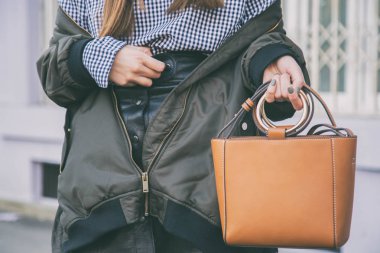 moda detayları, kahverengi zarif çantasını tutan kadın kapatın. Pötikareli onay üst ve bir bombardıman ceket poz ideal bahar kıyafet accessories.fashion blogger.