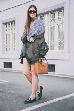 mükemmel bahar moda kıyafet. güneş gözlüğü, Pötikareli onay topaç, siyah etek, büyük boy bombardıman ceket, loafer'lar ve kahverengi bir çanta giyen şık genç kadın. Blogger sokakta poz moda.