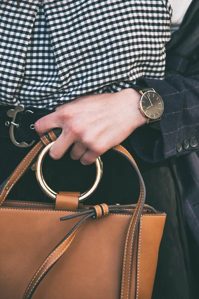 Nahaufnahme Modedetails, junge Geschäftsfrau hält ihre braune elegante Tasche. trägt schwarz-goldene Uhr. ideales Frühlings-Outfit-Zubehör. — Stockfoto