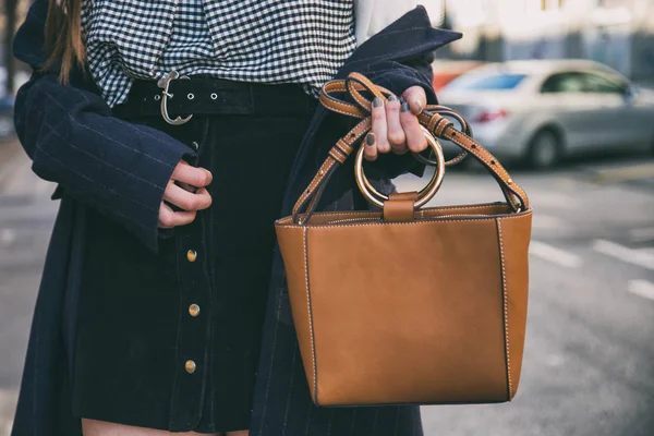Menutup rincian mode, wanita bisnis muda memegang tas elegan coklatnya. memakai jam tangan hitam dan emas. aksesoris pakaian musim semi yang ideal . — Stok Foto