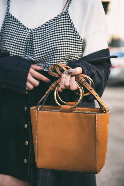 Cerrar los detalles de moda, mujer de negocios joven sosteniendo su bolso elegante marrón. vistiendo reloj negro y dorado. accesorios ideales del equipo de primavera . — Foto de Stock