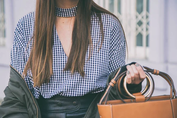 Détails de mode de près, femme tenant son sac brun élégant. idéal tenue de printemps accessories.fashion blogueur posant dans un top à carreaux gingham et une veste de bombardier . — Photo