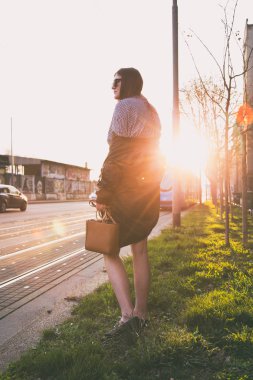 mükemmel bahar moda kıyafet. Pötikareli onay topaç, siyah etek, büyük boy bombardıman ceket, loafer'lar ve kahverengi bir çanta giyen moda kadın. Blogger sokakta günbatımında poz moda.