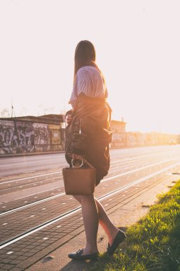 mükemmel bahar moda kıyafet. Pötikareli onay topaç, siyah etek, büyük boy bombardıman ceket, loafer'lar ve kahverengi bir çanta giyen moda kadın. Blogger sokakta günbatımında poz moda.