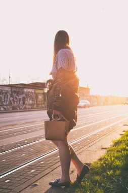 mükemmel bahar moda kıyafet. Pötikareli onay topaç, siyah etek, büyük boy bombardıman ceket, loafer'lar ve kahverengi bir çanta giyen moda kadın. Blogger sokakta günbatımında poz moda.