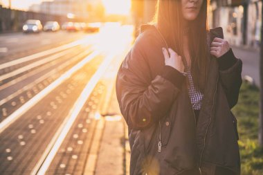 mükemmel bahar moda kıyafet. Pötikareli onay topaç, siyah etek, büyük boy bombardıman ceket, loafer'lar ve kahverengi bir çanta giyen moda kadın. Blogger sokakta günbatımında poz moda.