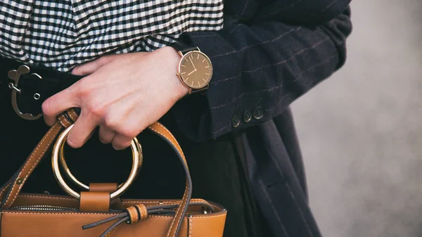 Close up fashion details, young business woman holding her brown elegant bag. wearing black and golden watch. ideal spring outfit accessories. — Stock Photo, Image