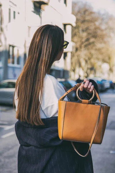 Detalj av en modern kvinna som bär en marinblå oversized kappa, en vit skjorta och en brun trendig handväska. perfekt våren mode outfit. — Stockfoto