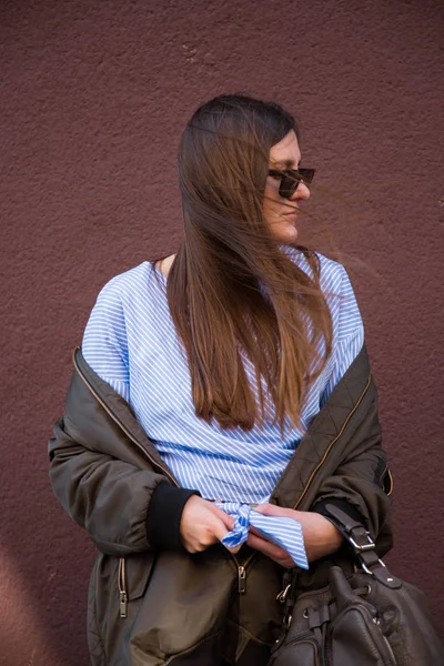 완벽 한 봄 패션의 상에 유럽 패션 블로거 입고 선글라스, 전면 매듭와 폭격기 재킷 유행 크로스 오버 스트라이프 블라우스. 머리에 바람. — 스톡 사진