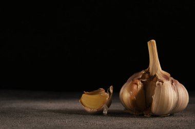 Siyah arkaplanda karanfil olan bir sarımsak başı.