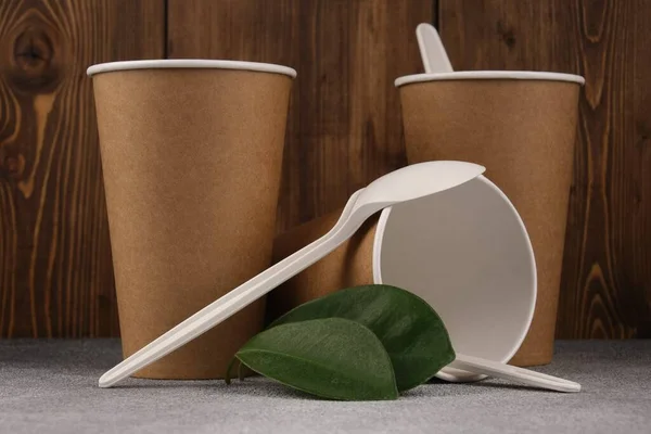 Three Cardboard Cups Green Leaves Lie Concrete Surface Wooden Background — Stock Photo, Image