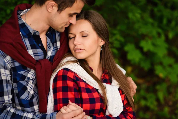 Stylish young couple in shirts and jeans while walking in the forest. A beautiful girl with her handsome boyfriend in a hug s. Close up portrait.