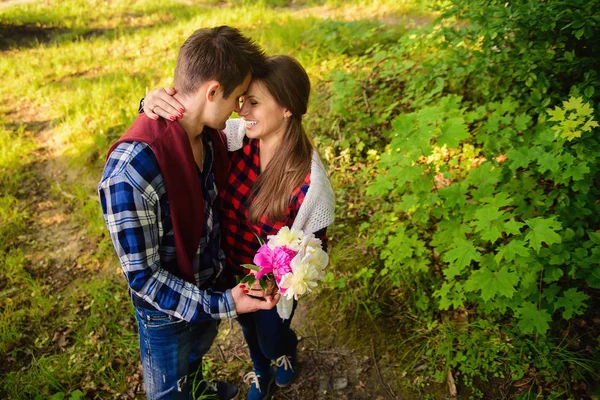 Snygga unga par i skjortor och jeans medan promenader i skogen. Den vackra charmiga flickan och hennes stiliga pojkvän lutade mot varandra. — Stockfoto