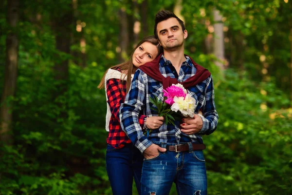 Elegante giovane coppia in camicie e jeans mentre passeggia nel bosco. L'affascinante ragazza posò la testa sulla spalla del suo bel ragazzo . — Foto Stock