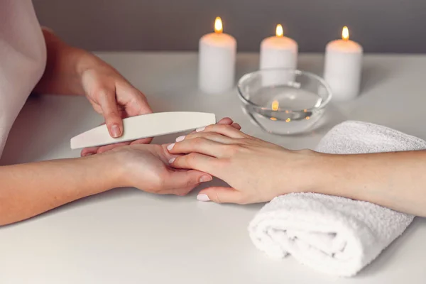 Spa salon. Piękna kobieta ręce posiadające paznokci zgłoszenia z pilnik do paznokci przez makijażystki. Zabieg kosmetyczny, manicure, kobiece strony — Zdjęcie stockowe