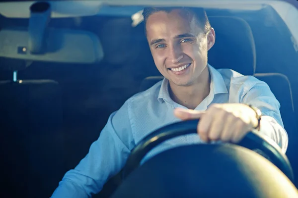 Attractive handsome successful man in white shirt driving an expensive car