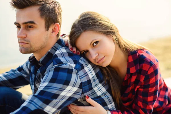 Elegante giovane coppia in camicie e jeans mentre cammina sulla riva di un lago. Bella ragazza affascinante abbraccia il suo bel ragazzo. Ritratto da vicino . — Foto Stock