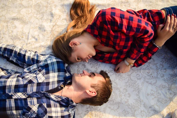 Elegante giovane coppia in camicie e jeans mentre passeggia lungo la riva del lago. Una bella ragazza attraente e il suo bel ragazzo sdraiato su una coperta e sorridente l'un l'altro. Da vicino. . — Foto Stock