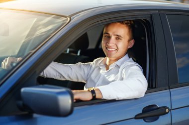 Çekici gülümseyen yakışıklı beyaz gömlek pahalı bir araba sürüş