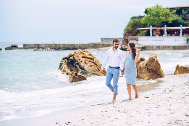 Şık genç bir çift deniz kıyı yürürken elele.