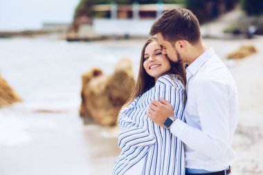 Güzel bir hamile kadın ve birbirlerine karşı yaslanmış ve bir beyaz ile kaplı saygın erkeğini ekose sahil üzerinde çizgili. Güzel genç çift, gelecekteki anne.