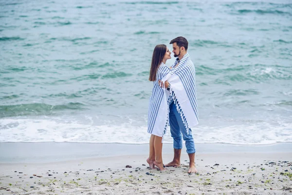 美しい妊娠中の女性と海岸で白いストライプ プラッドとかぶってにもたれて彼女の立派な男。素敵な若いカップルは、将来の親. — ストック写真