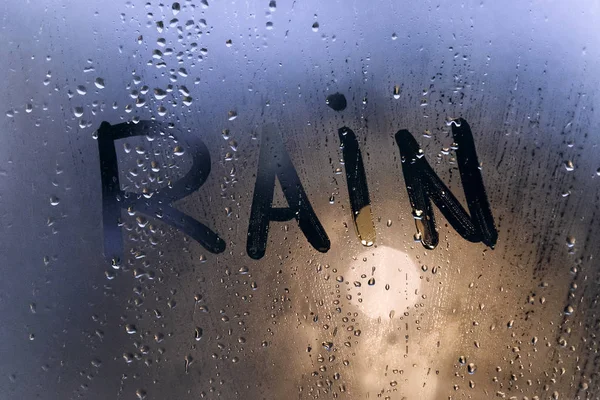 Clima lluvioso, la inscripción lluvia en el vaso sudoroso . — Foto de Stock