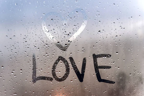 Rainy weather, the inscription love and hand-drawn heart on the sweaty glass. — Stock Photo, Image