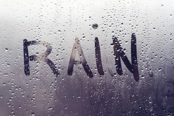 Tempo chuvoso, a chuva inscrição no vidro suado . — Fotografia de Stock