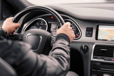 Businessman driving luxury modern car in the city. Close up man's hand on the wheel of the car. clipart