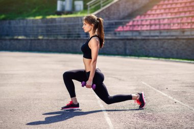Vücut kas germe fitness kız sadium eğitim, daha önce üzerinde sıcak yapıyor ultra violet dumbbells ile. Kadın atlet bacaklar kardiyo egzersiz için hazırlanıyor. Etkin kız açık yapıyor.