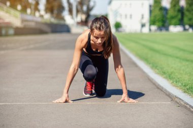 Gitmek için hazır! Kadın atlet başlangıç çizgisine Stadyumu parçanın üzerinde bir çalıştırmak için hazırlanıyor. Fitness kız düşük bir başlangıç çalıştırmak hazırlanıyor. Sağlıklı yaşam tarzı.