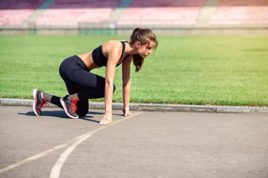 Gitmek için hazır! Kadın atlet başlangıç çizgisine Stadyumu parçanın üzerinde bir çalıştırmak için hazırlanıyor. Fitness kız düşük bir başlangıç çalıştırmak hazırlanıyor. Sağlıklı yaşam tarzı.