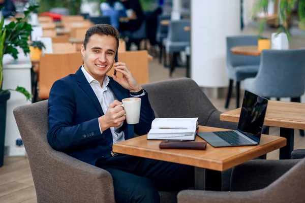 Overworked businessman have coffee break and speaking on smartphone. Cryptocurrency mining. Gold and silver bitcoin coin. Electronic virtual money investment. Selective focus.