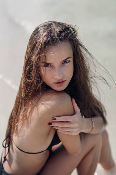 Красивая девушка в черном купальнике на летнем пляже. Модный портрет загорелой женщины на берегу моря
.