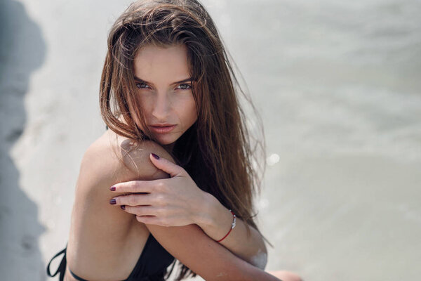 Красивая девушка в черном купальнике на летнем пляже. Модный портрет загорелой женщины на берегу моря
.