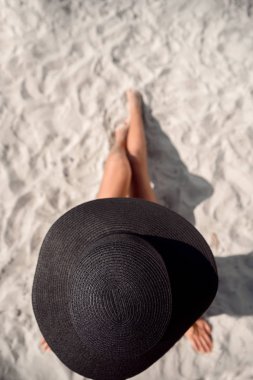 Genç kadın bir sahilde oturup güneşin tadını. Plajda tabaklanmış kız rahatlatıcı. Yaz tatil kavramı. Üstten Görünüm.