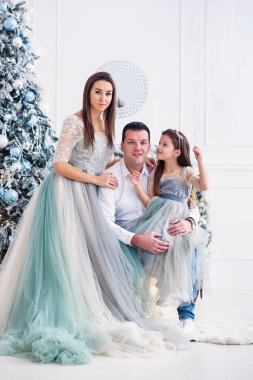 Neşeli ebeveynler ve tatlı kızları içeride Noel ağacının yanında eğlenip oynuyorlar..