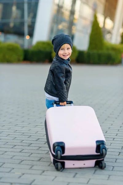 Söt liten resenär flicka drar rosa resväska mot flygplatsen. — Stockfoto
