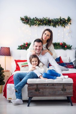 Ebeveynler ve çocukları Noel ağacının yanında oturuyorlar.