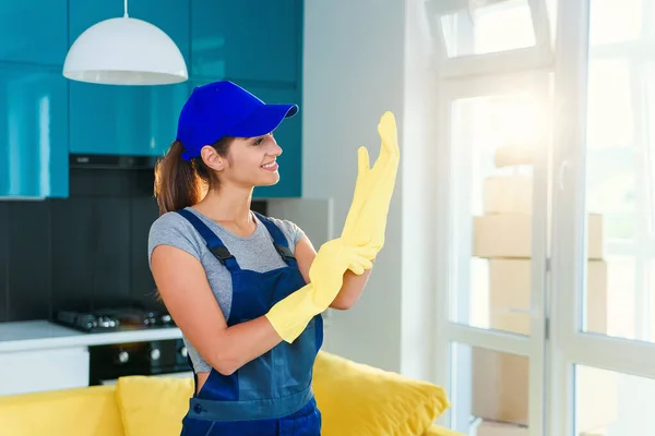 Веселая девушка в специальной рабочей одежде в желтых резиновых перчатках и готовится к уборке кухни в квартире . — стоковое фото