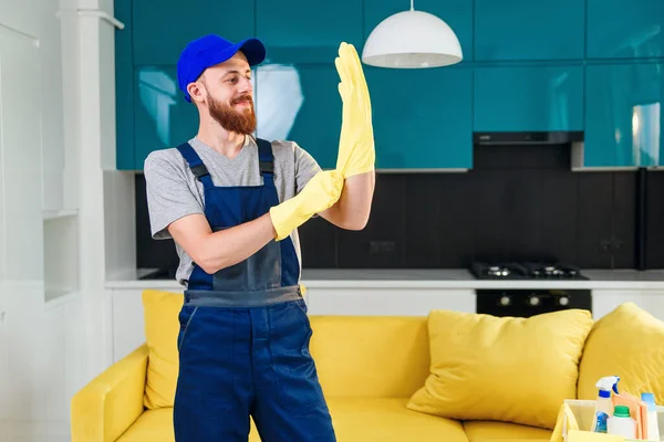 Привлекательный парень с ухоженной бородой от уборки в защитных резиновых перчатках для чистки домашней кухни — стоковое фото