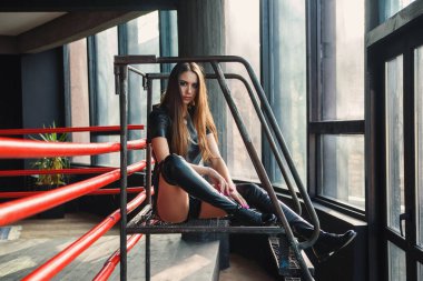 Deri şort ve ceket giyen çekici manken boks ringinde poz veriyor..