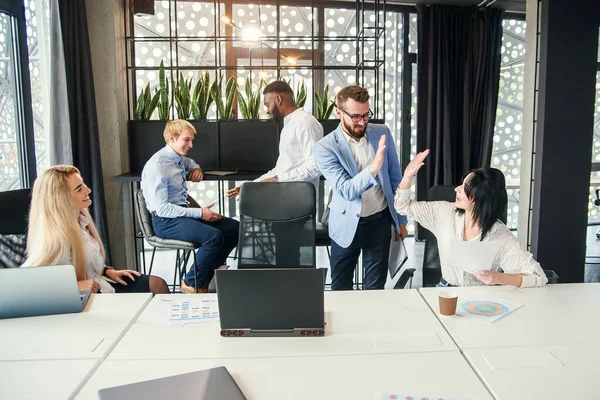 Empresarios saludando a sus colegas de oficina con cinco altos antes del inicio de los trabajos bajo proyecto de negocio conjunto en la oficina moderna . — Foto de Stock