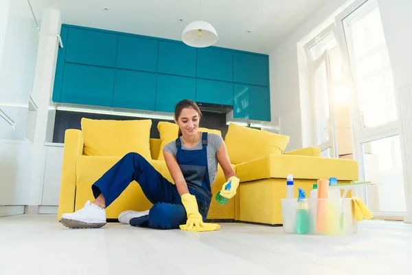 Gelukkige vrouwelijke huishoudster dweilen vloer met wasmiddelen en doek in appartement. Concept schoonmaakdiensten. — Stockfoto