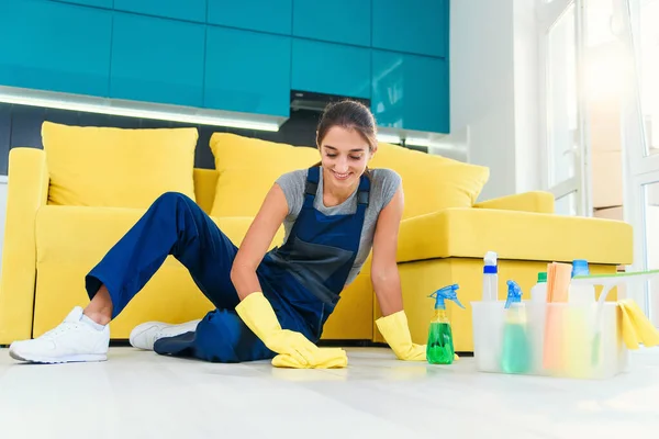 Gelukkige vrouwelijke huishoudster dweilen vloer met wasmiddelen en doek in appartement. Concept schoonmaakdiensten. — Stockfoto