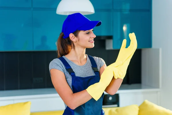 Молодая счастливая женщина надевает желтые резиновые перчатки и готовится к уборке . — стоковое фото