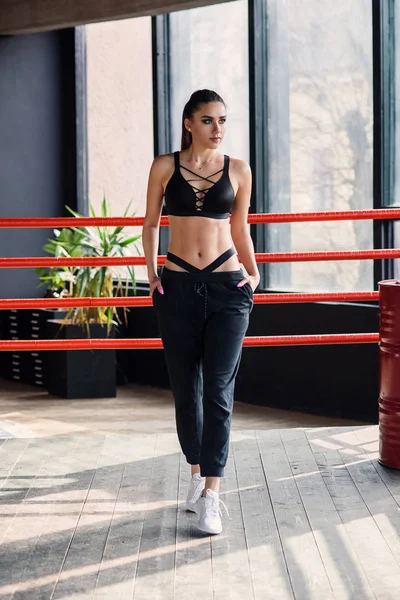 Sexy fitness menina no sportswear stands inclinado no cordas de boxe anel . — Fotografia de Stock