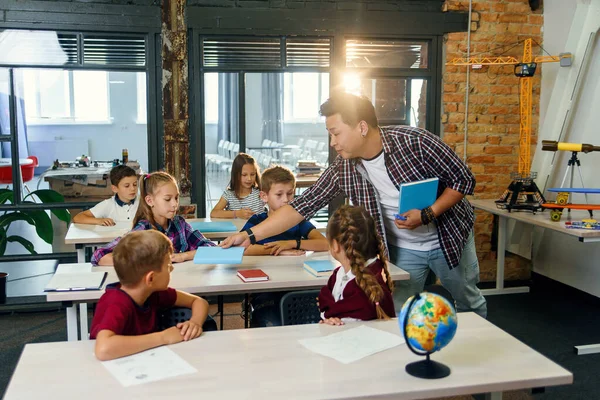 Grupo de alumnos de la escuela primaria sentados en los escritorios y pasar el examen en el aula de la escuela inteligente moderna . — Foto de Stock