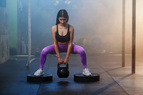 Joven mujer en forma haciendo ejercicio con pesas en el gimnasio . —  Fotos de Stock